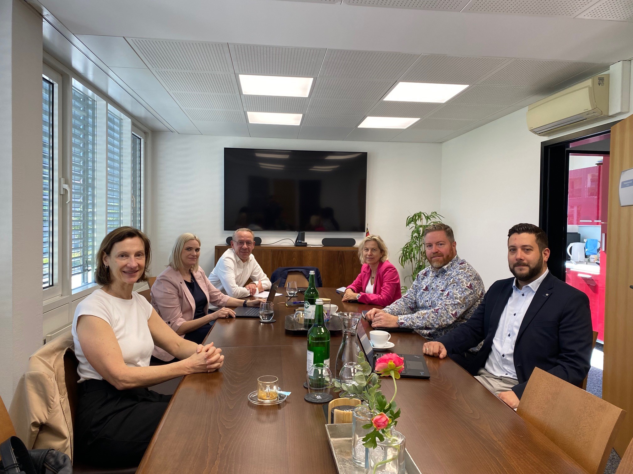 Professionelles Meeting in modernem Konferenzraum mit vielfältigen Teilnehmern bei produktivem Austausch.